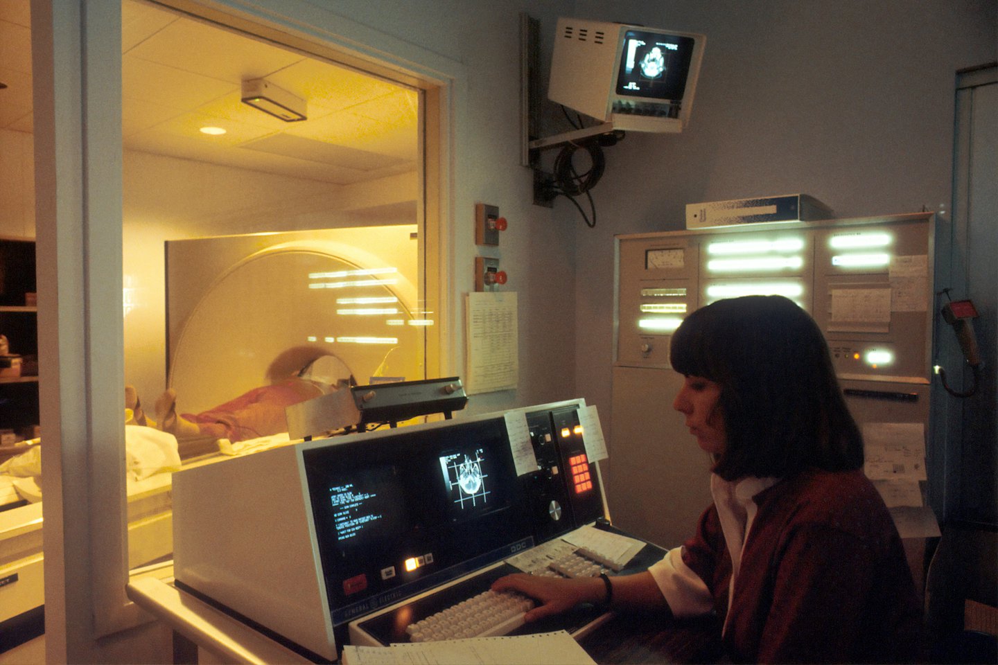 Technician monitors patient scan on imaging equipment console.